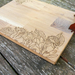 Planche à découper en chêne gravée à la découpe laser, avec un motif floral.