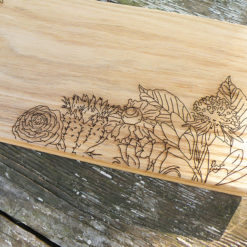 Planche à découper en chêne gravée à la découpe laser, avec un motif floral.